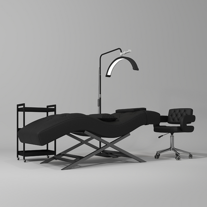 Black massage table with a lamp and chair on a gray background
