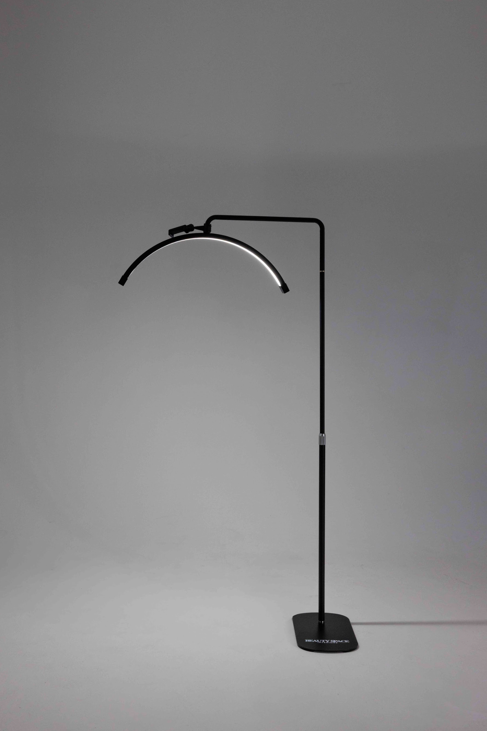 A black floor lamp with a flexible neck, standing in a relaxed S shape, with a smaller loop at the top and a solid base.
